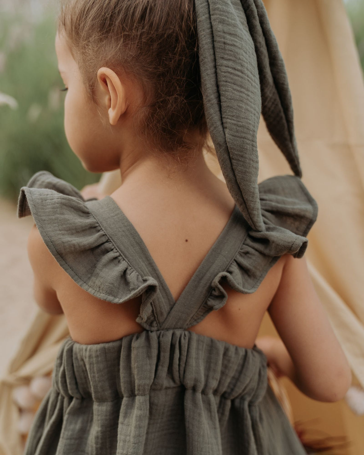 Girl model wearing the River Dress in Soft Khaki Green.