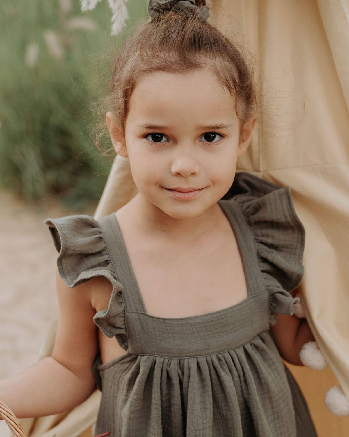 Girl model wearing the River Dress in Soft Khaki Green.