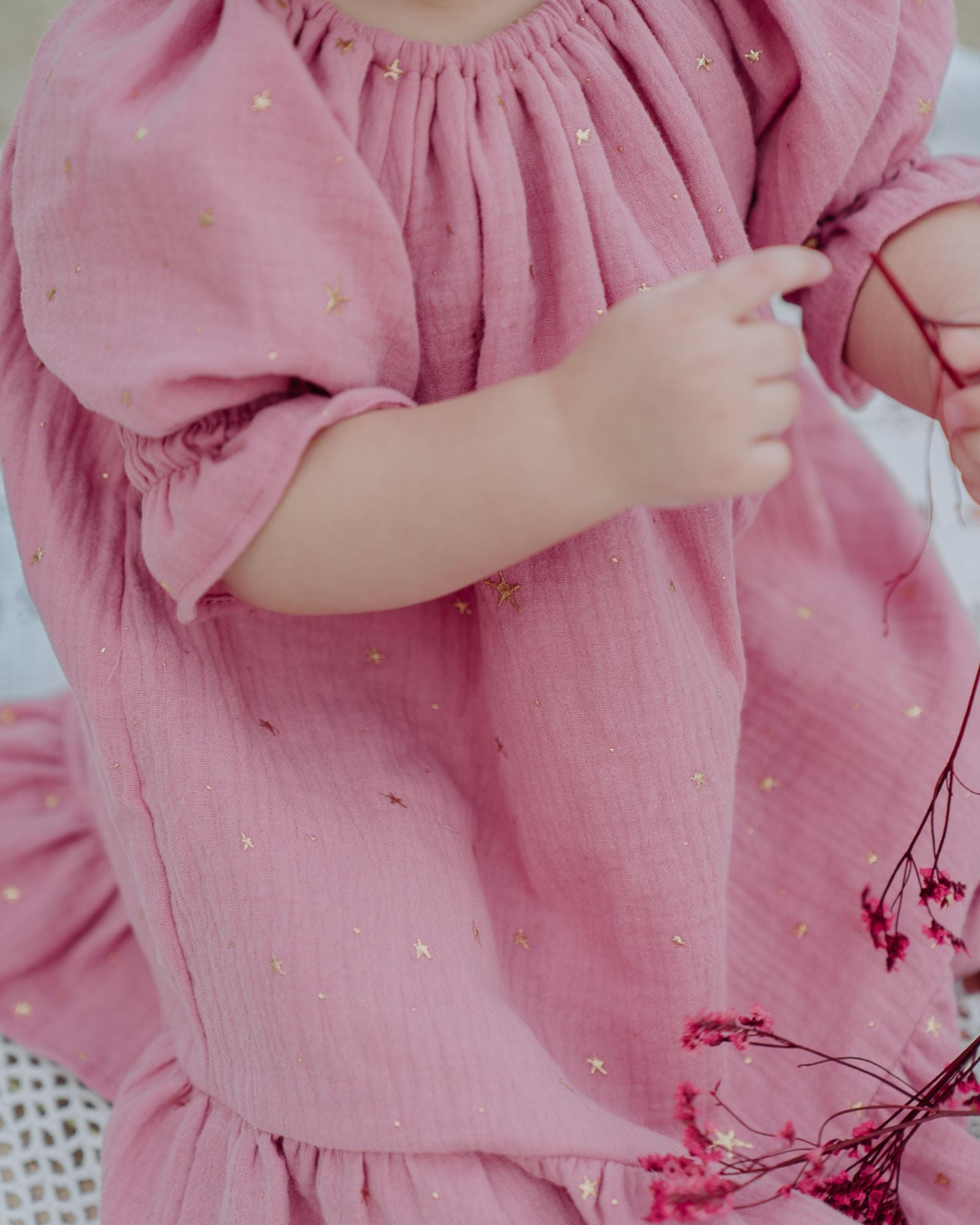 Baby Girl wearing the Alexa Dress in Rose Pink with Golden Drop Stars.