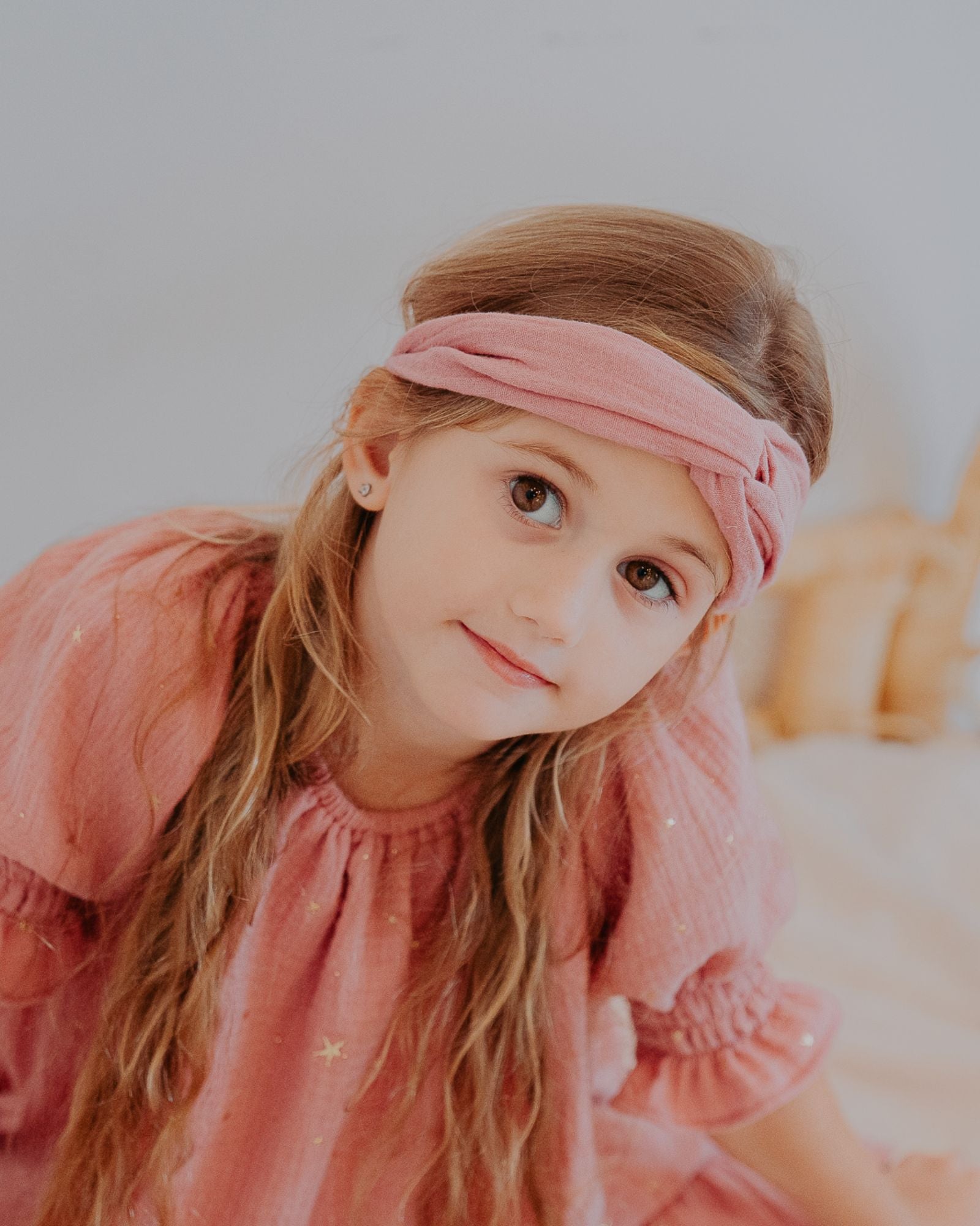 Girl model wearing the Twisted Headband in Blush Pink with the Alexa Dress in Drop Stars Rose Pink.