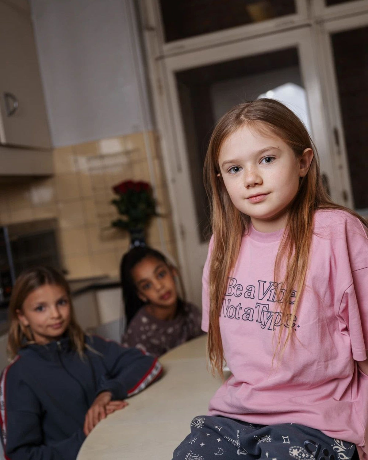 Girl wearing the pink Be A Vibe kids T-shirt by Cos I Said So in an AW26 campaign image