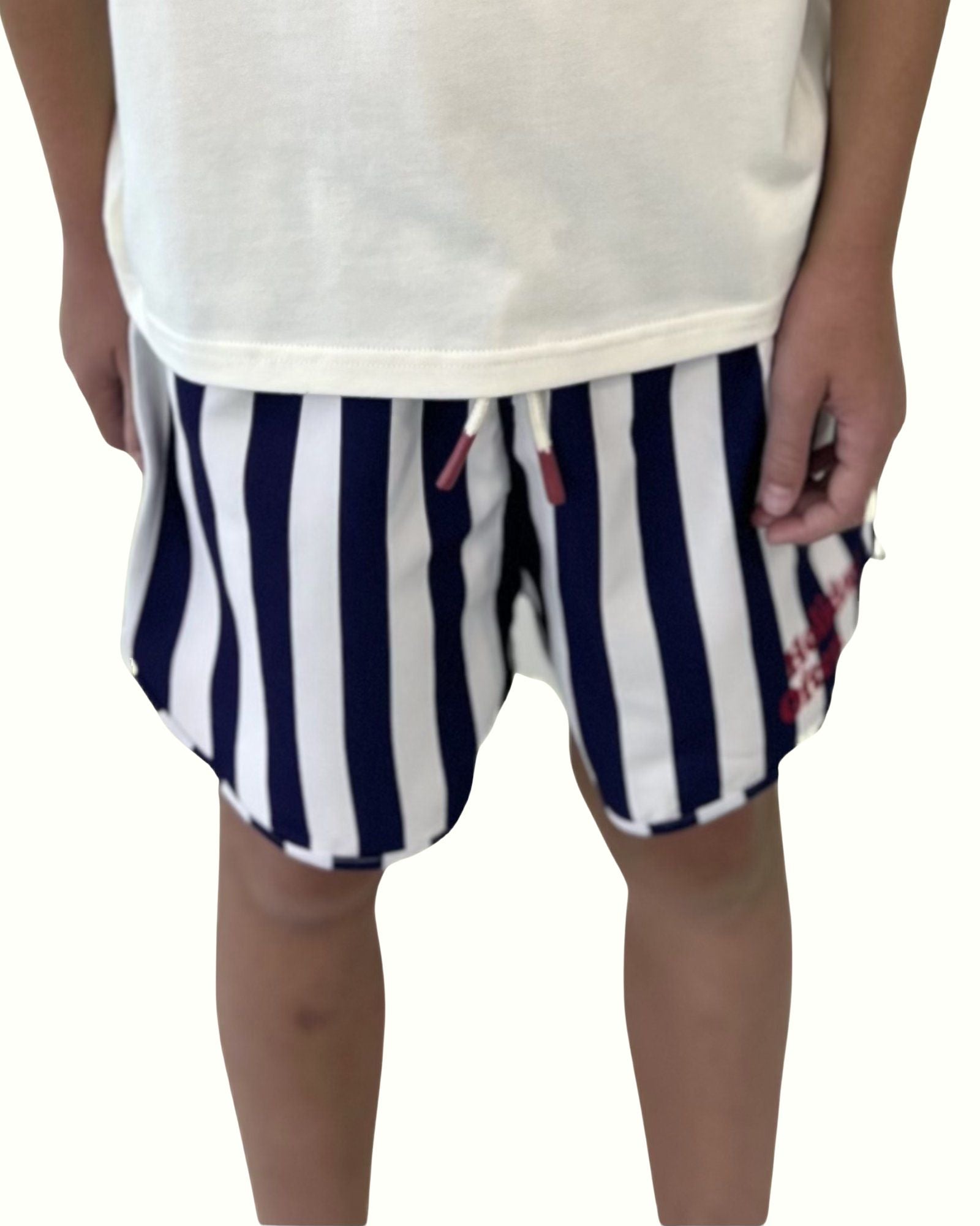 boy model showing the swim shorts holiday often by Cos I Said So in navy blue and white stripes with caption holiday often in red