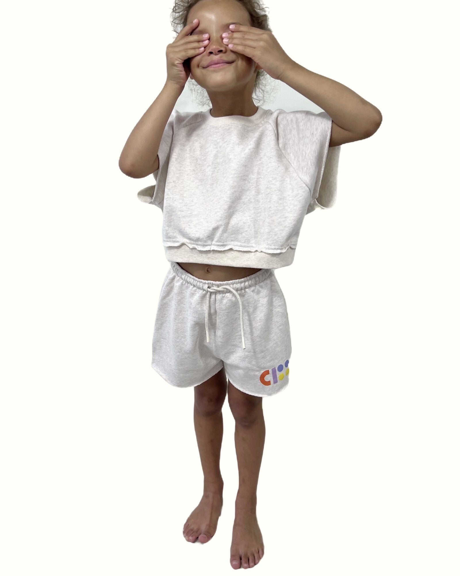 girl model wearing the cut off jog shorts in off white by Cos I Said So with the matching jog top by Cos I Said So