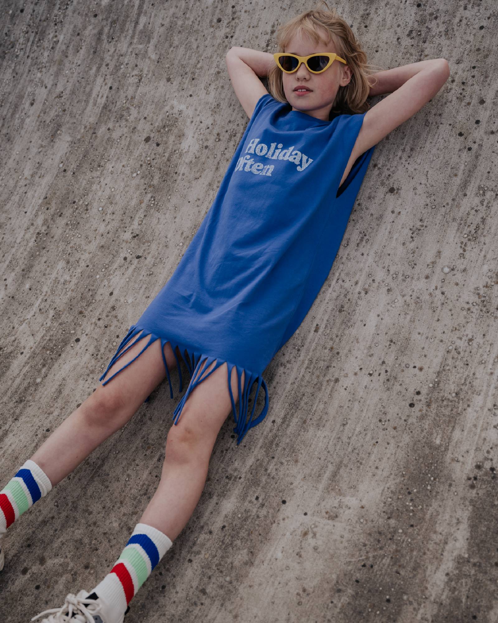 girl model wearing the fringe dress in ultramarine blue with the caption holiday often in white, paired with the retro socks