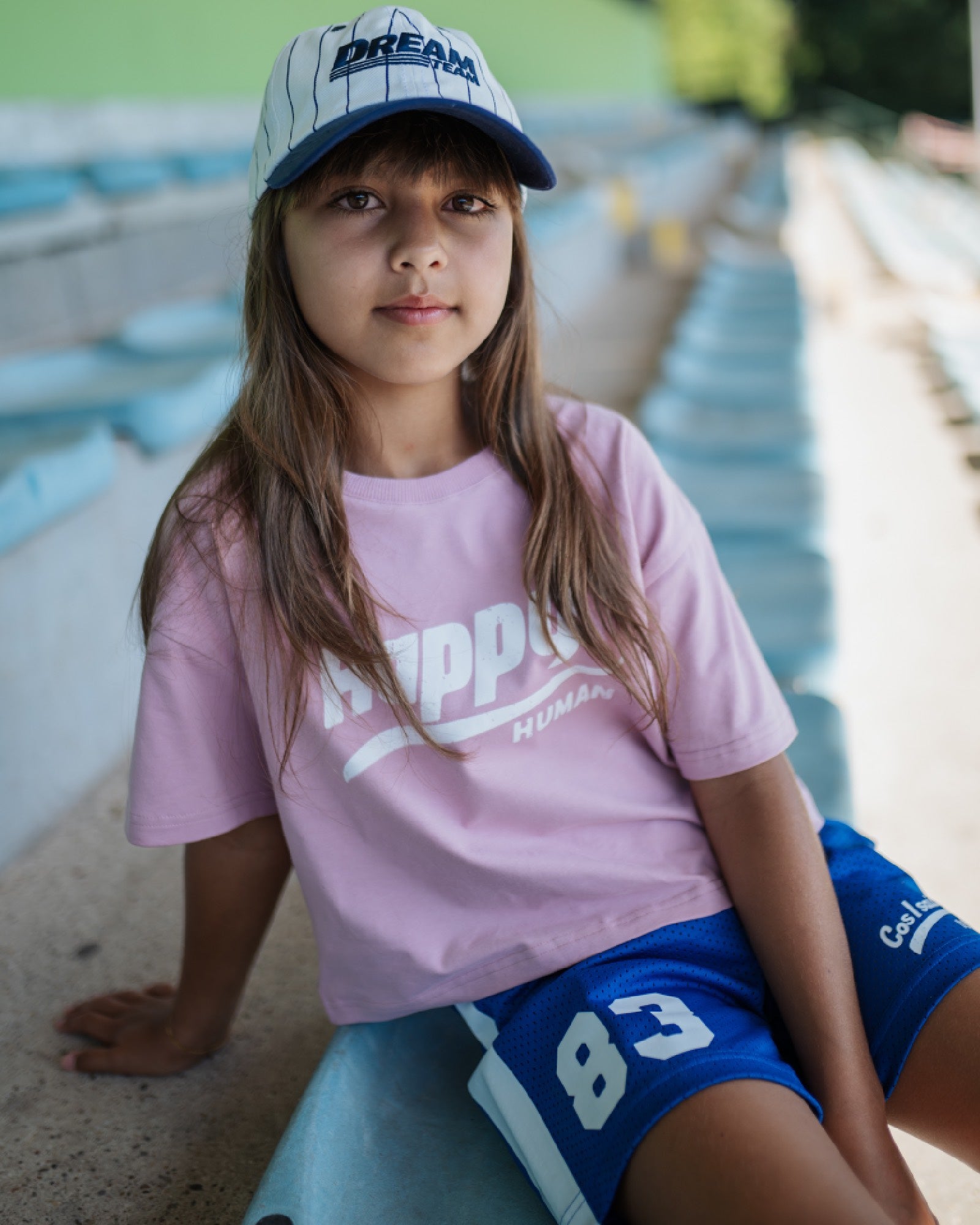 girl model wearing the happy human crop t-shirt with the mesh track shorts and the dream team cap in pin stripes