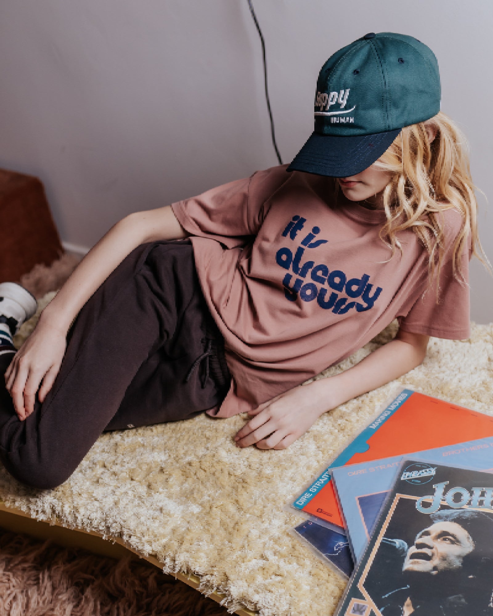 girl model wearing the it is already yours t-shirt in burlwood with the happy human cap in moss green