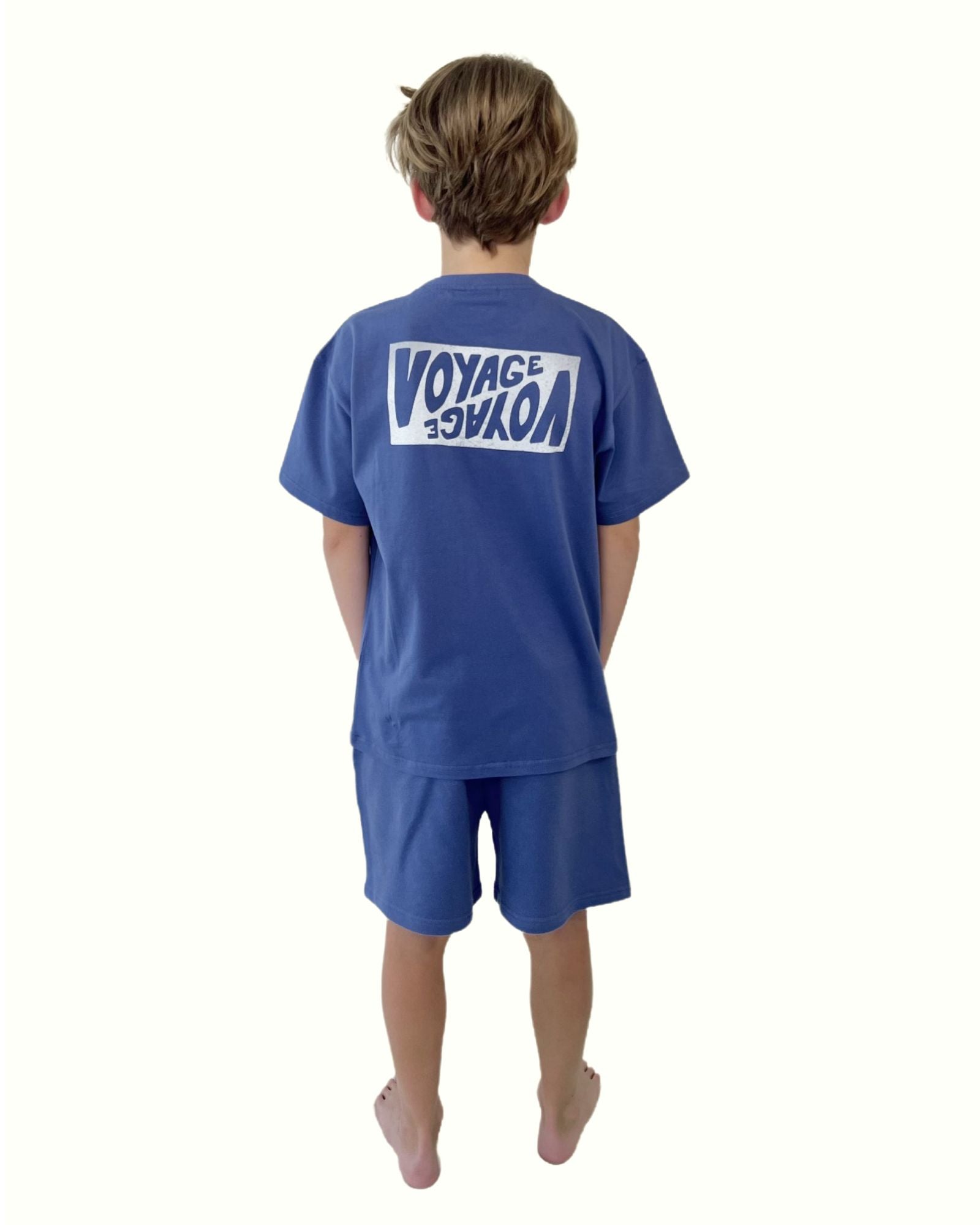 boy model wearing the voyage t-shirt in ultramarine blue by Cos I Said So with the matching jog shorts in ultramarine blue from the back