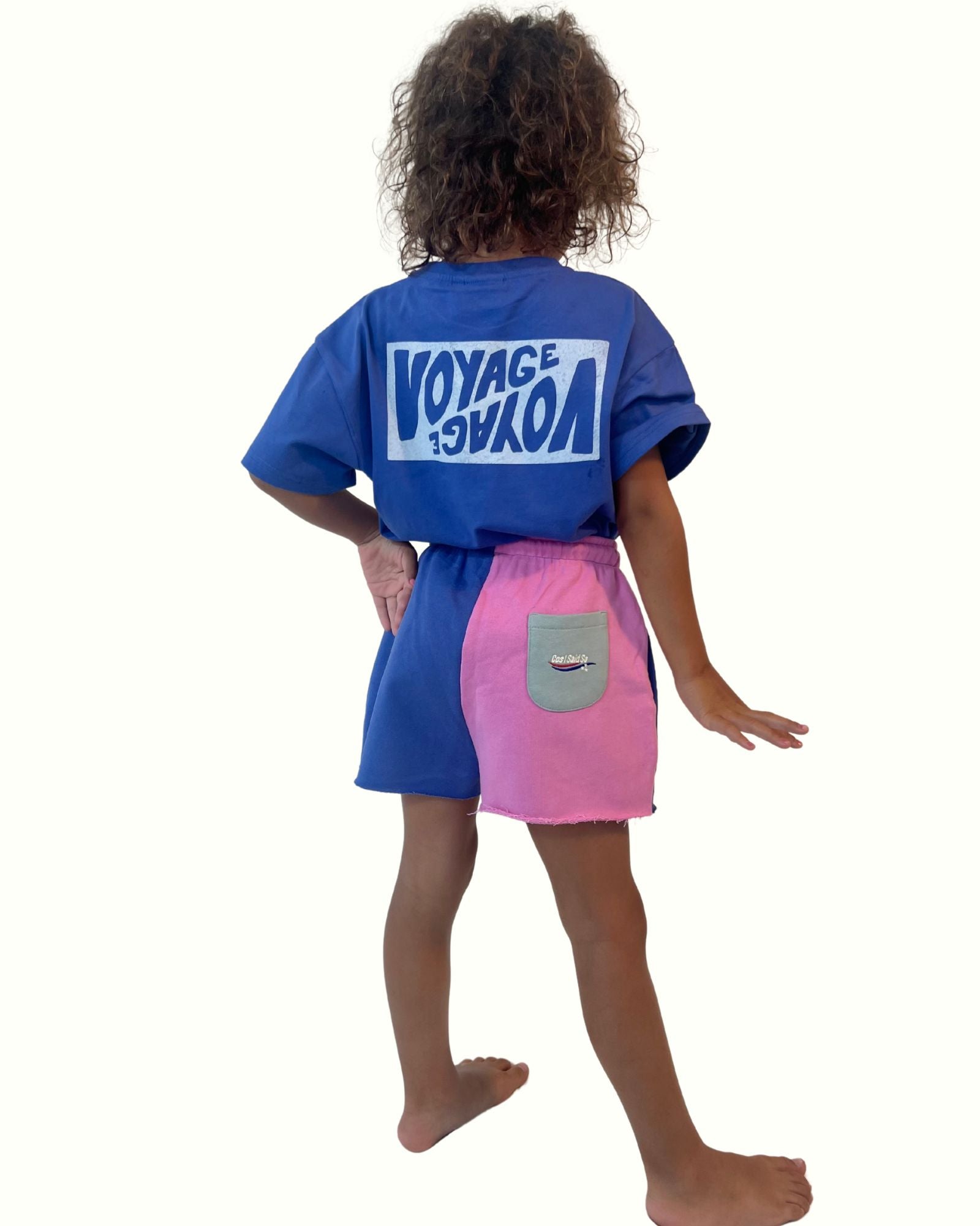 girl model wearing the voyage t-shirt in ultramarine blue by Cos I Said So with the matching cut off jog shorts colorblock from the back
