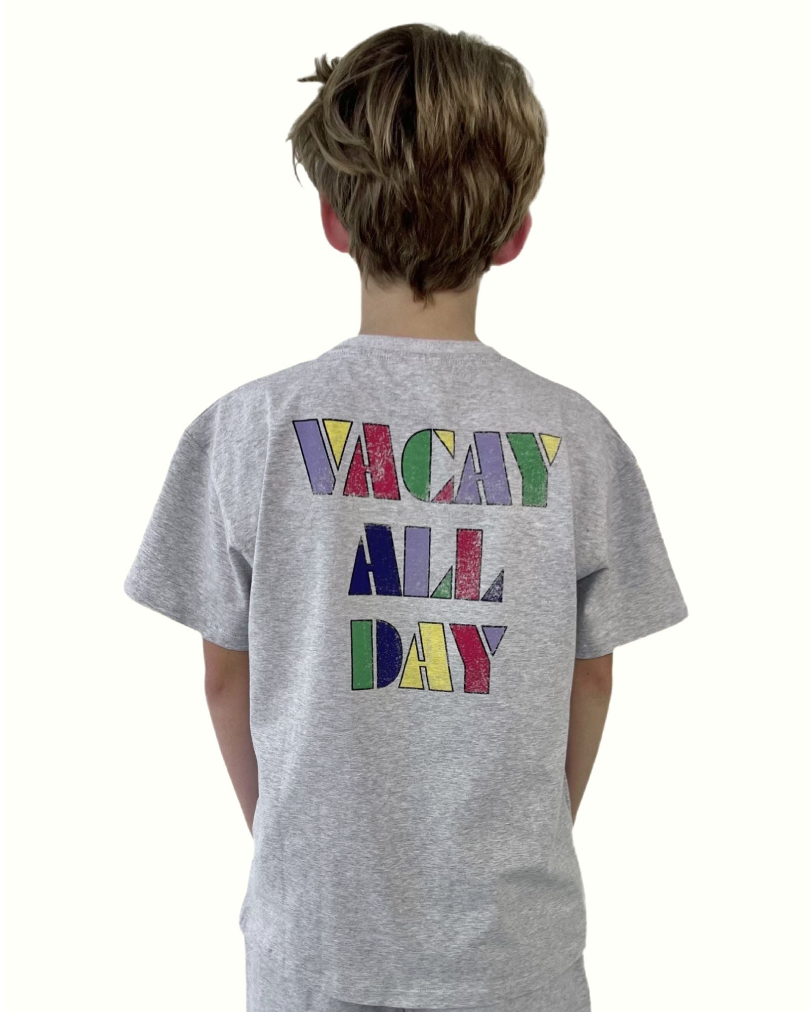 boy model showing the backside of the vacay all day t-shirt in the color grey with caption vacay all day in colorful letters, in soft organic cotton by Cos I Said So