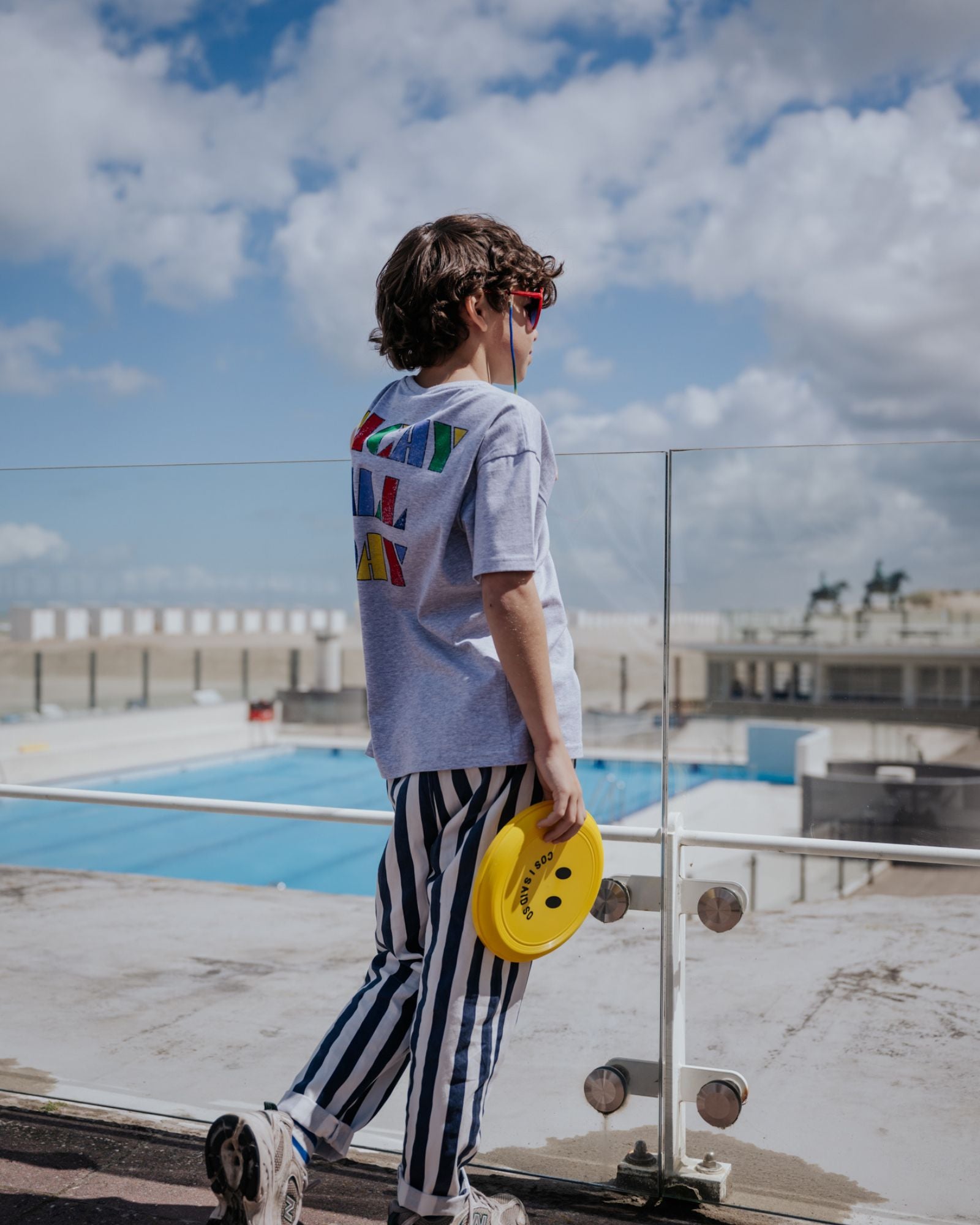 boy model wearing the vacay all day t-shirt in the color grey in soft organic cotton from the back