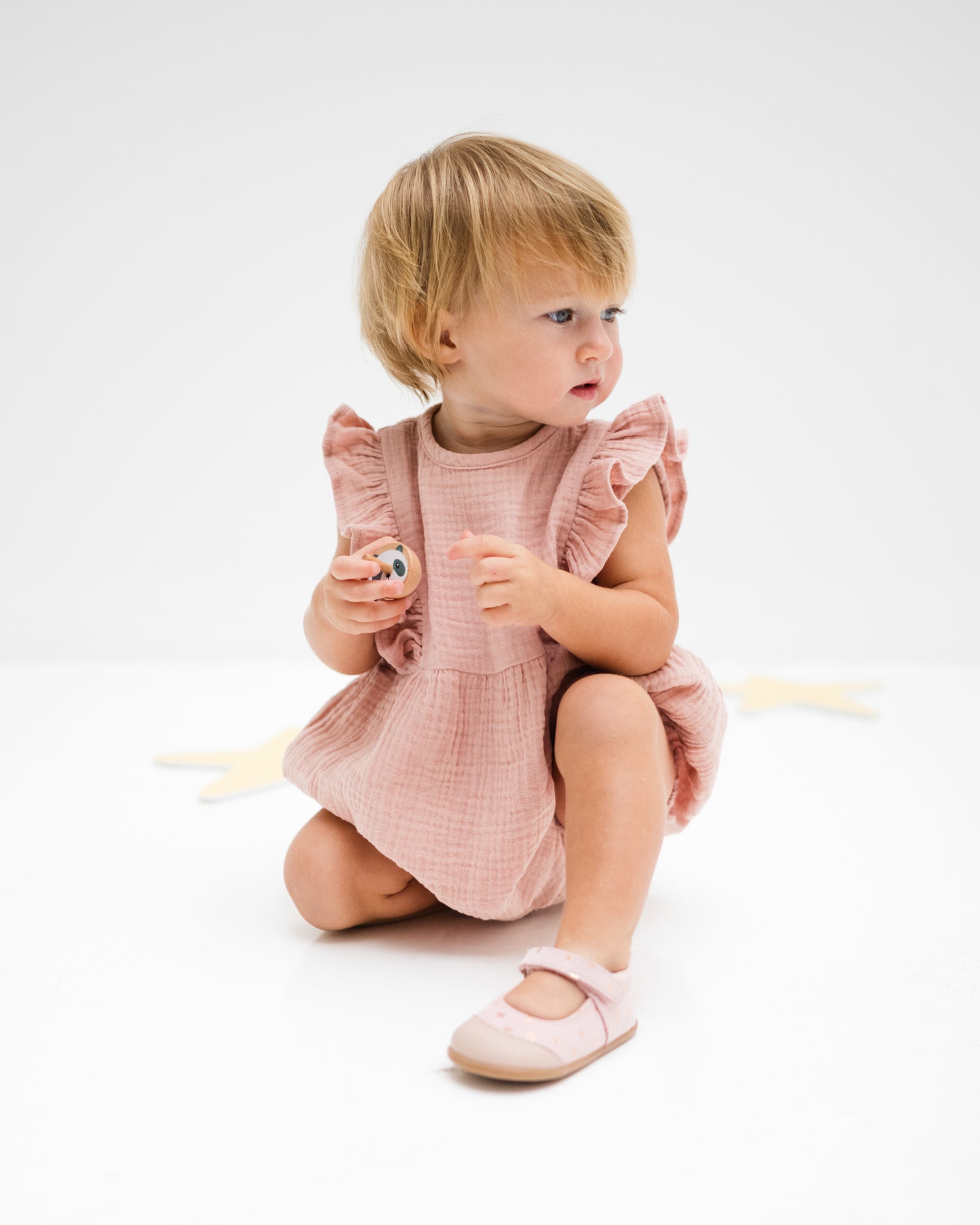 baby girl of 12 months wearing the Rose romper in soft pink in soft organic muslin cotton