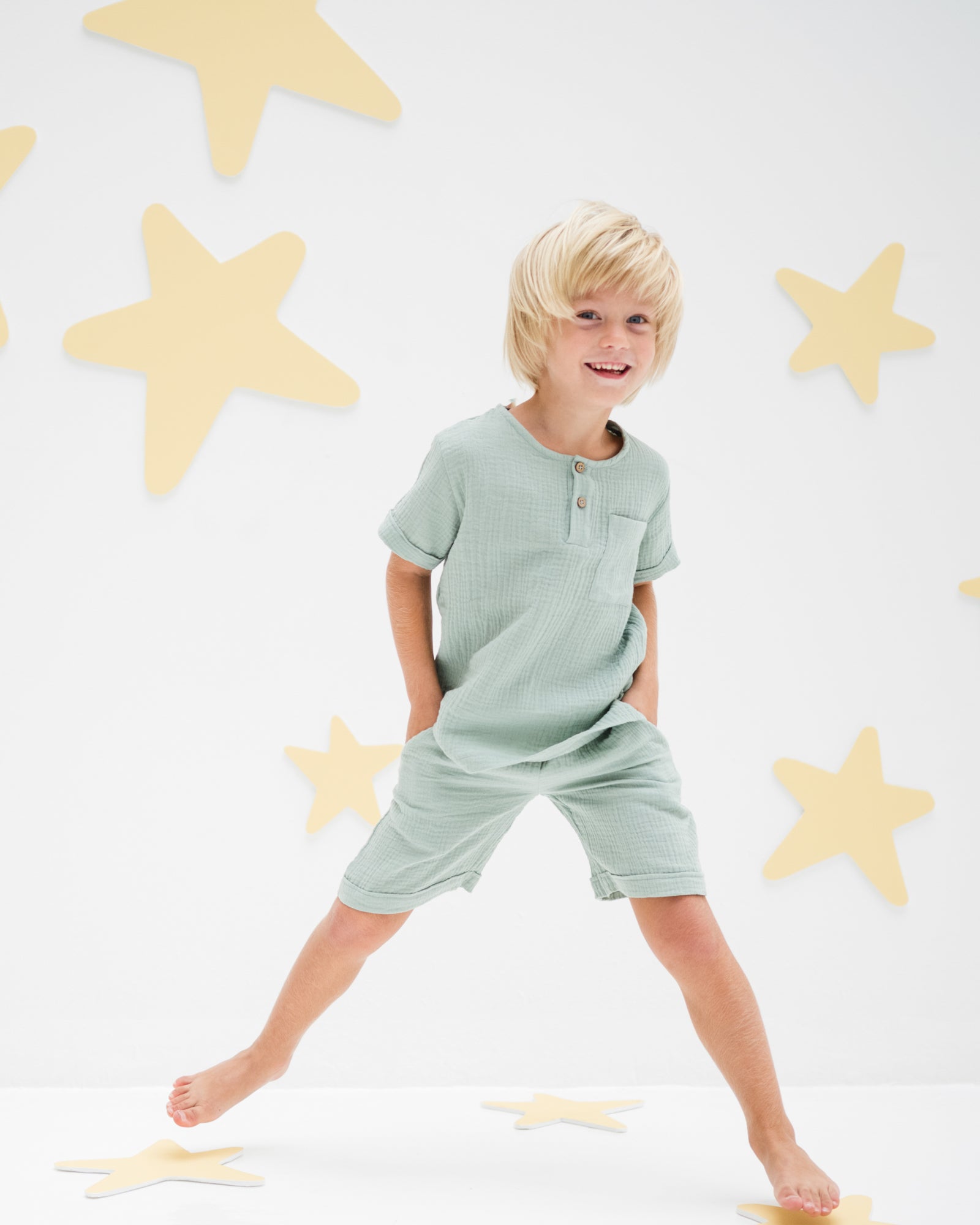 boy model wearing the charlie shirt combined with the julian shorts in sage green soft organic muslin cotton
