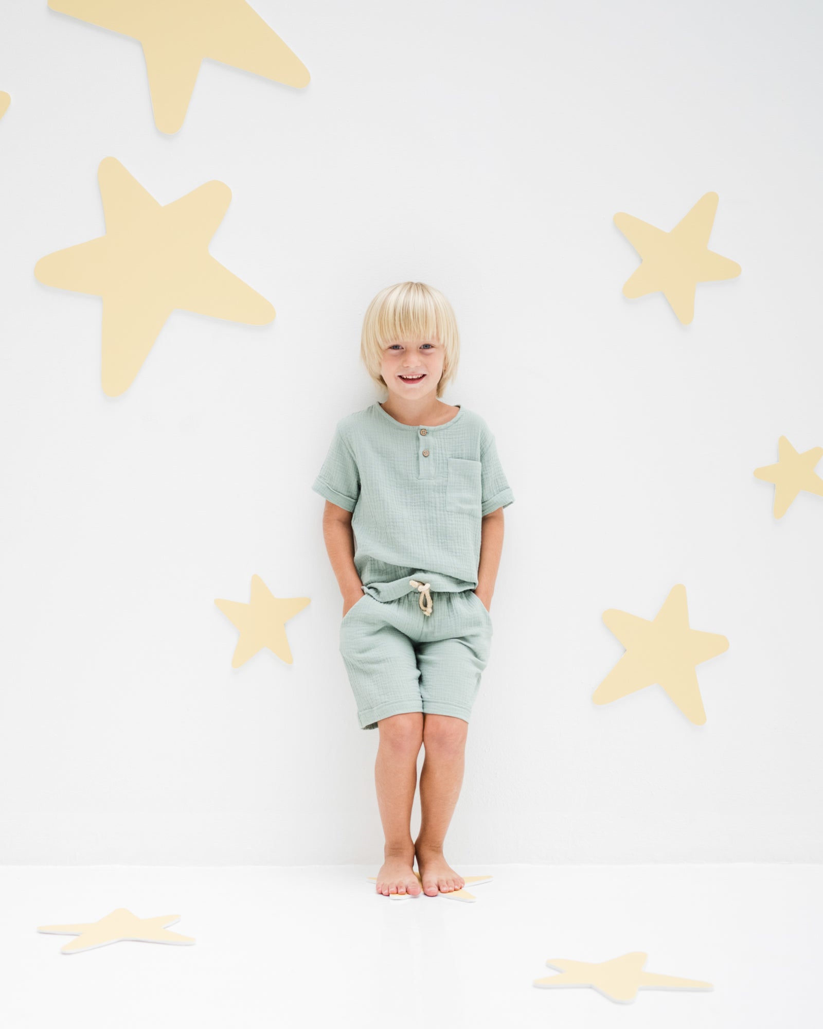 boy model showing the julian shorts in sage muslin cotton combined with the charlie shirt in sage muslin