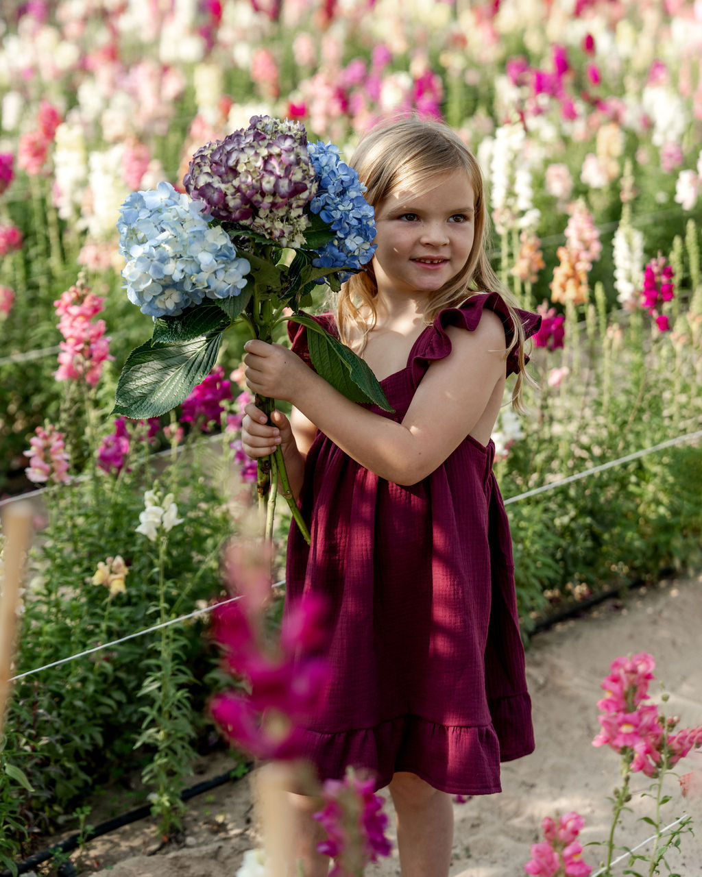 girl model wearing the River dress with frilled straps in aubergine muslin cotton