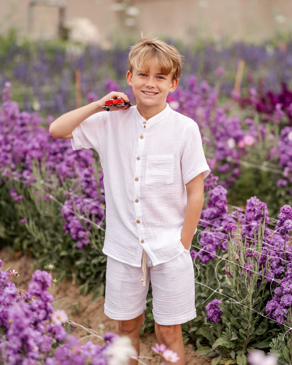 10-year-old boy wearing the raphael shirt with matching julian shorts in white muslin in a flowefield