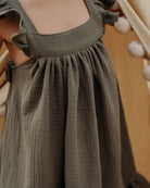 Girl model wearing the River Dress in Soft Khaki Green.
