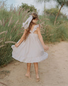 Girl model wearing the River Dress by Les Vedettes in Striped Beige and White Seersucker.