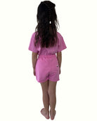 girl model wearing the happy human t-shirt in fuchsia with the matching cut off jog shorts in fuchsia by Cos I Said So from the back