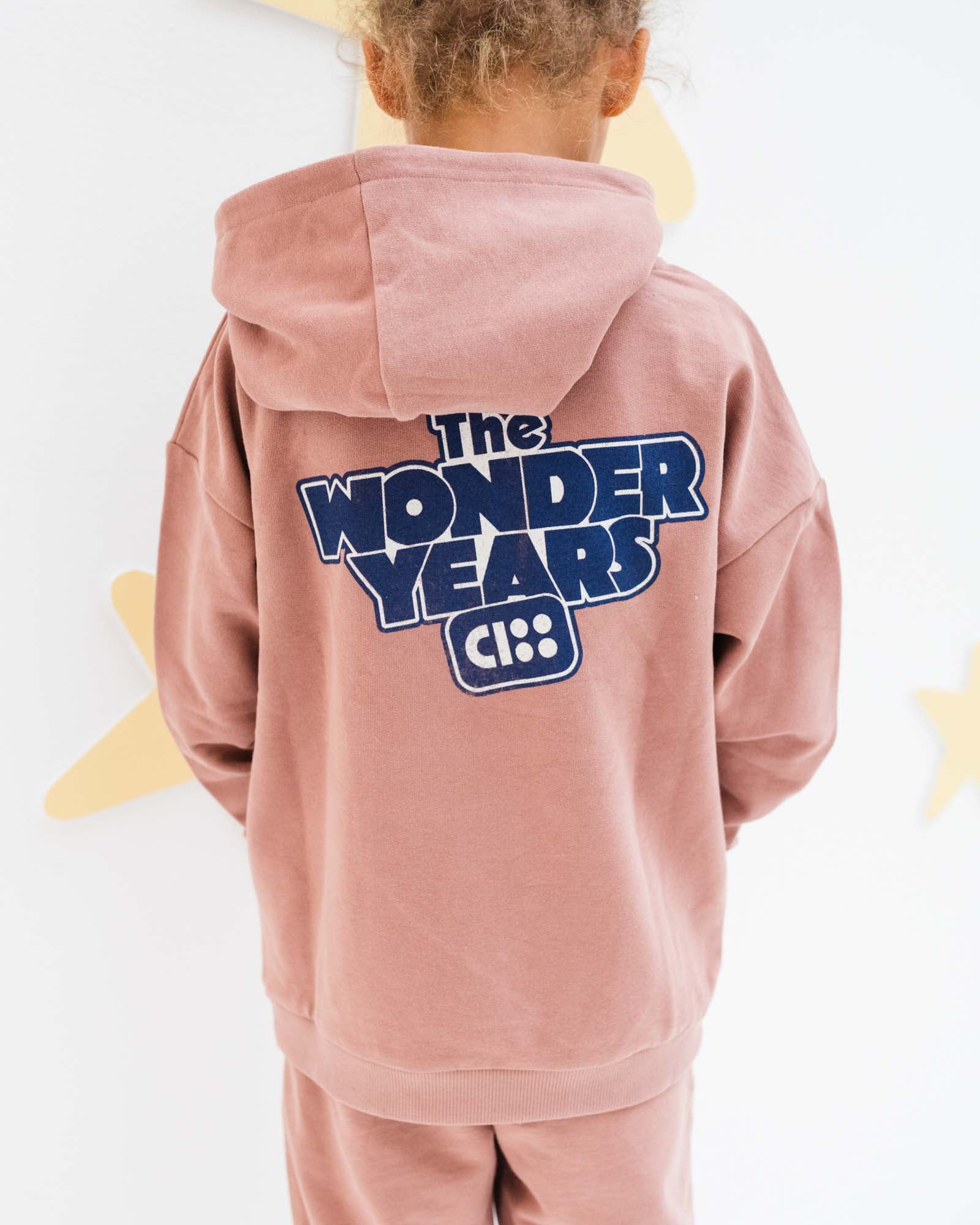 7-year-old girl model showing the backside of the wonderyears hoodie in burlwood 