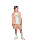 boy model wearing the summer camp t-shirt with the happy human sweater in praline and the jog shorts in praline, combined with the ciss socks logo