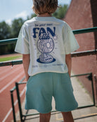 boy model showing the fan club t-shirt and the  jog shorts in agate green of cos I said so from the backside
