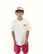 boy model showing the holiday often t-shirt with the jog shorts in poinsettia red and the holiday often cap