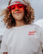 boy model wearinf the holiday often t-shirt in white with red caption holiday often in the left front side