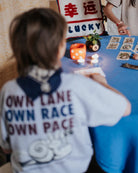 boy model showing the own lane t-shirt in grey melange from the back and it says own lane, own race, own pace with a graphic of a snail