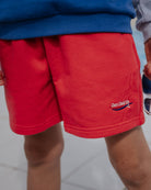 boy model wearing the jog shorts in the color poinsettia red 