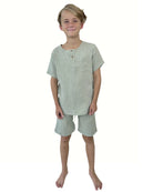 boy model wearing the boys shorts Julian by Les Vedettes in the color sage green in soft muslin cotton, combined with the boys top Charlie in sage green