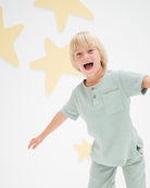 boy model wearing the charlie shirt in sage green soft organic muslin cotton
