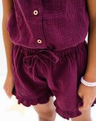 7-year-old girl wearing the Lilou top and matching Charlene shorts in a high quality aubergine muslin