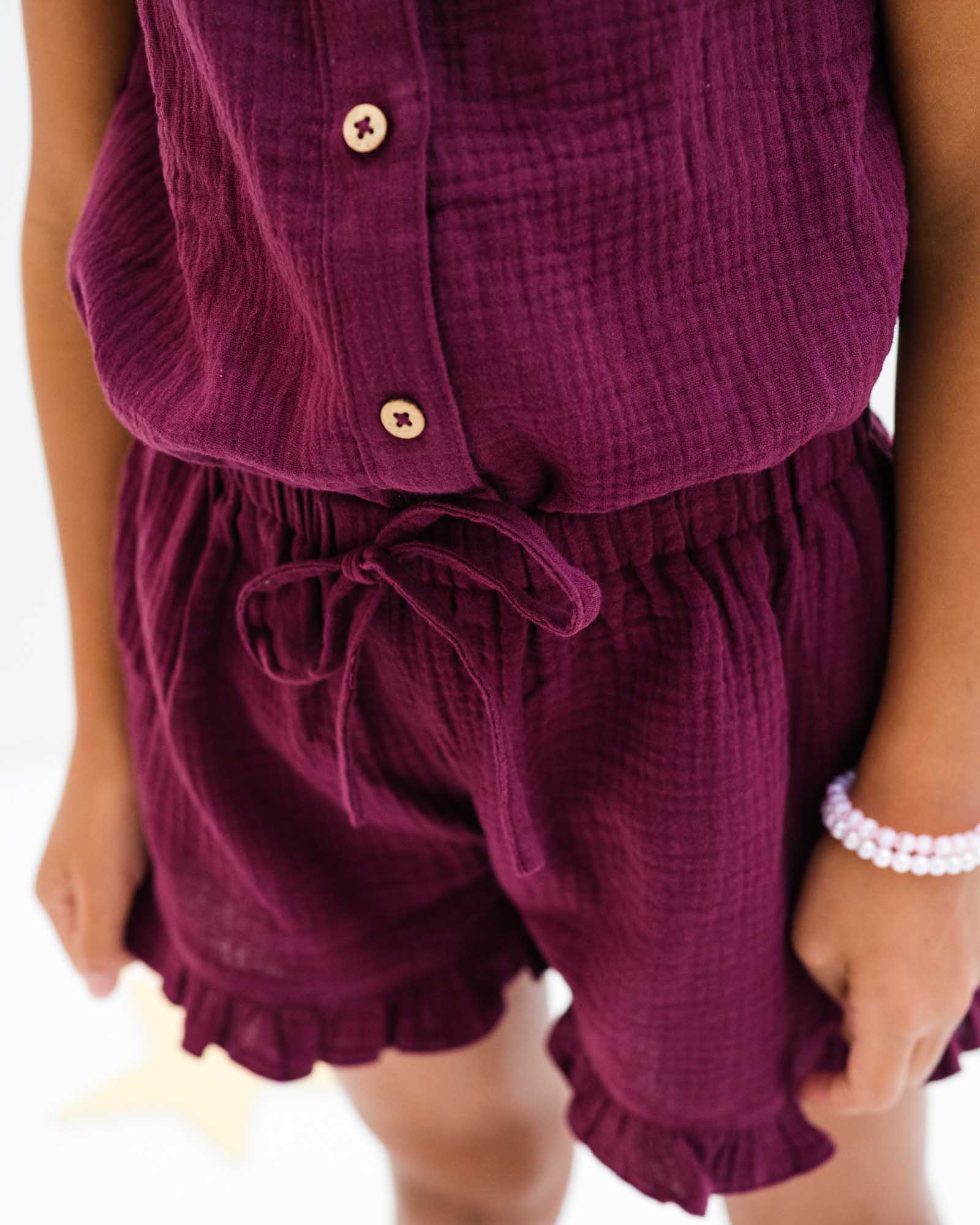 7-year-old girl wearing the Lilou top and matching Charlene shorts in a high quality aubergine muslin