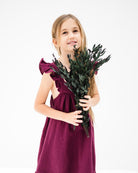 girk holding eucalyptus and wearing Riber in burgundy muslin