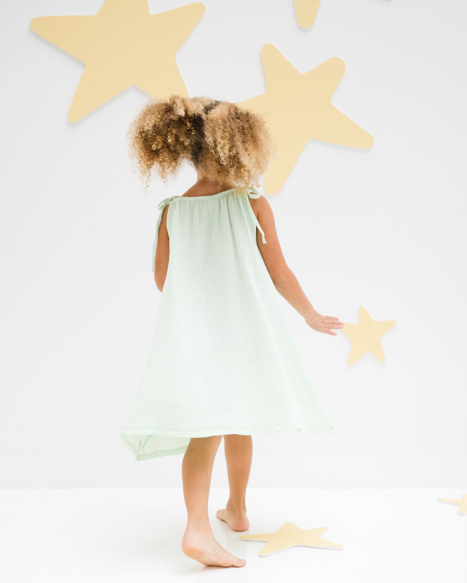 girl model showing the romy dress in soft mint muslin cotton from the back