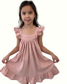 girl model wearing the stunning sleeveless River dress with frills on the shoulders in high quality soft pink muslin cotton by Les Vedettes, this dress is a best seller of Les Vedettes