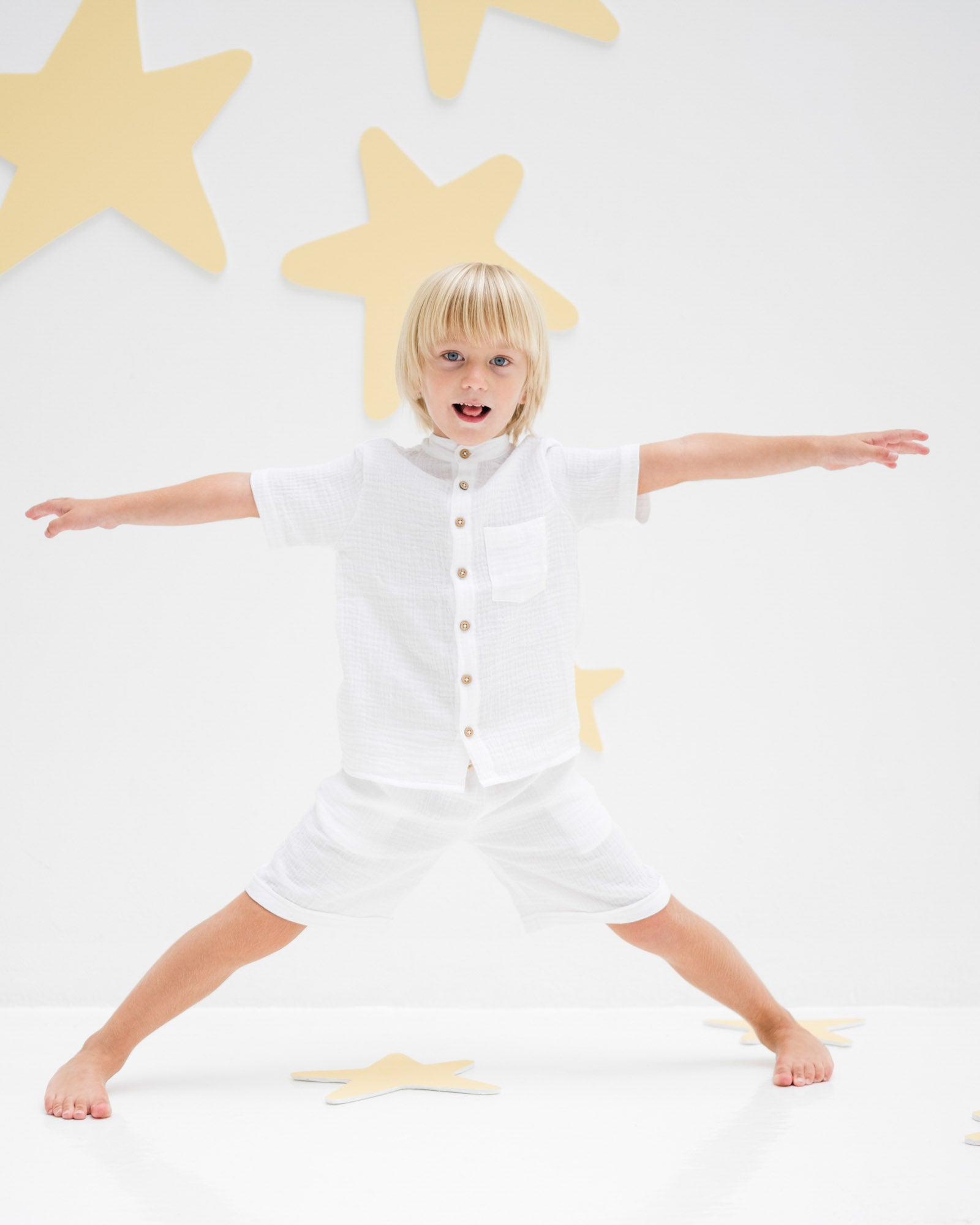 5-year-old boy stretching out in the comfy  raphael shirt and matching julian shorts in white