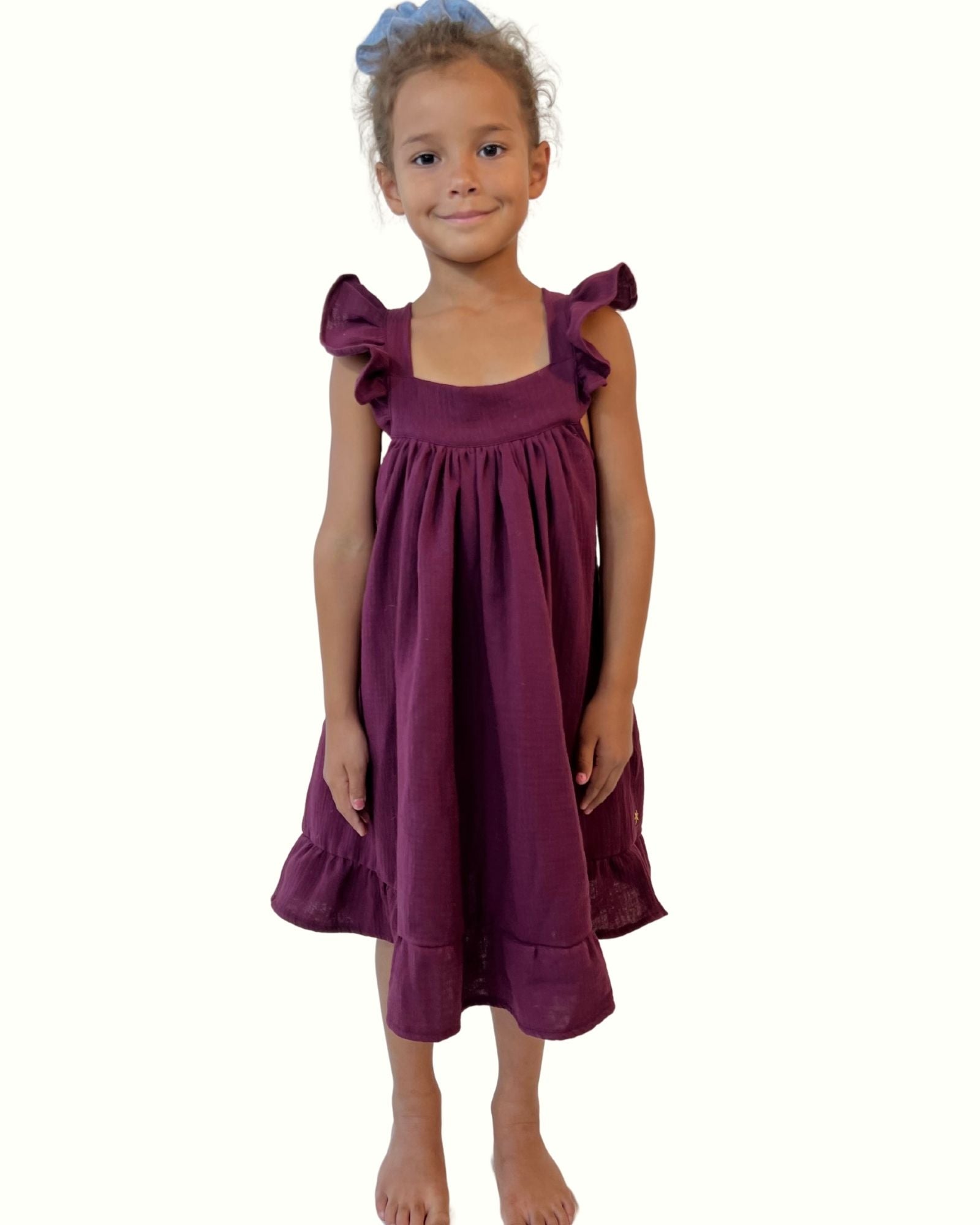 girl model wearing the stunning sleeveless River dress with frills on the shoulders in the rich color aubergine muslin cotton by Les Vedettes, this dress is a best seller of Les Vedettes