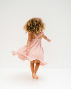 girl model wearing the river dress in soft pink muslin cotton showing the back