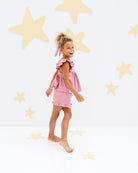 7-year-old-girl showing the charlene shorts in rose pink with golden stars from the side