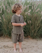 boy model wearing the Charlie Shirt in khaki green muslin cotton, matching the Julian shorts in khaki green muslin cotton