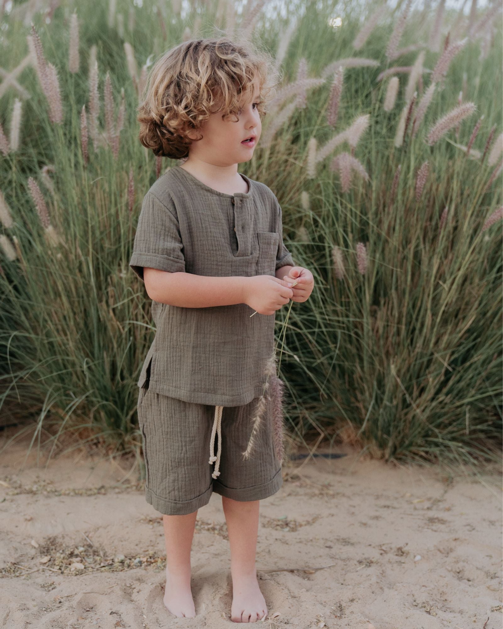 boy model wearing the Charlie Shirt in khaki green muslin cotton, matching the Julian shorts in khaki green muslin cotton