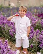 10-year-old boy wearing the raphael shirt with matching julian shorts in white muslin in a flowefield